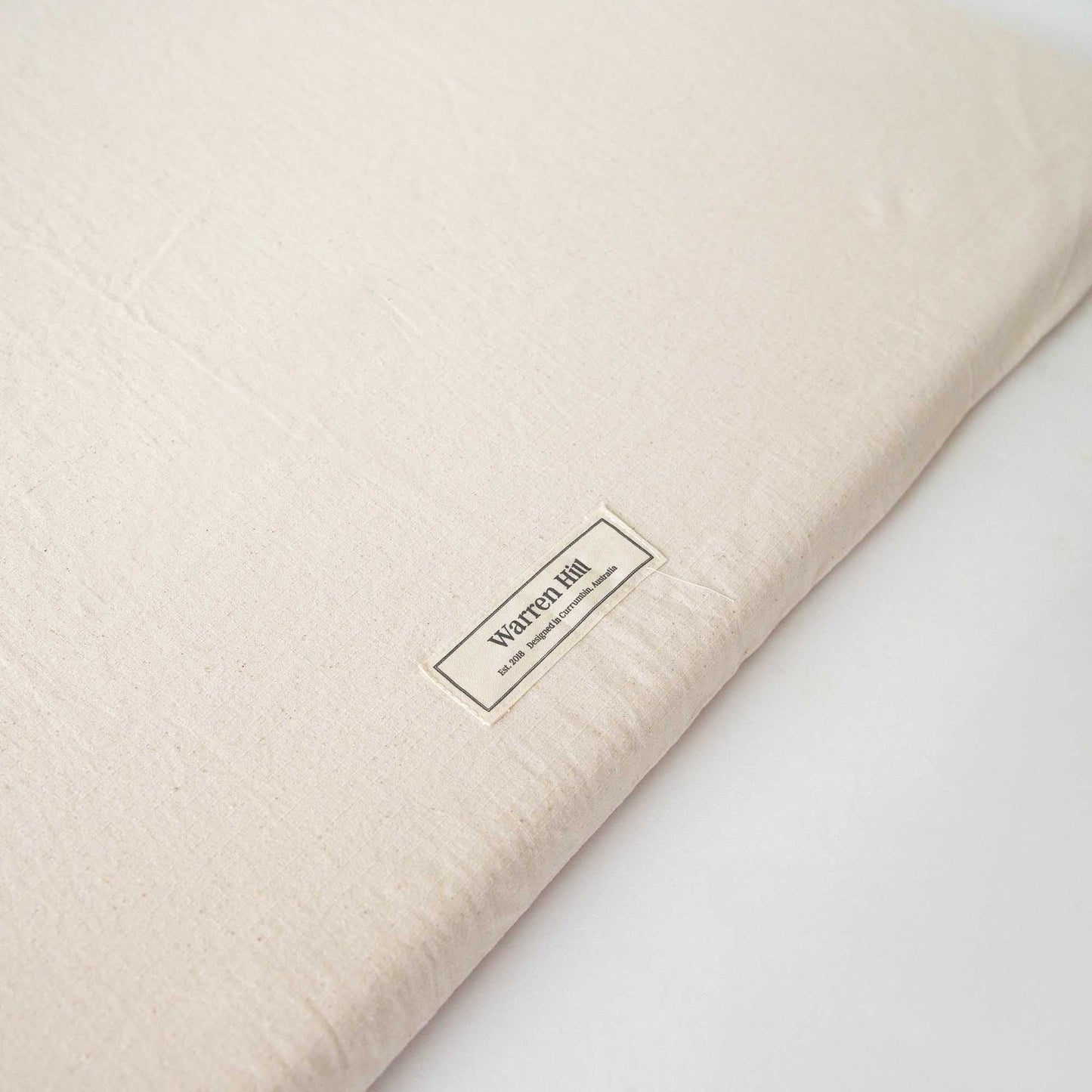 Detailed view of the Warren Hill label stitched onto the Light Natural Padded Play Mat.